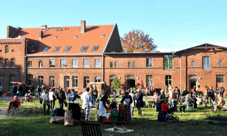 Foto StadtGut Blankenfelde (im Hintergund ein altes Backsteinhaus und im Vordergrund viele Menschen)